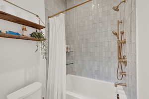 Bathroom featuring toilet and shower / bath combo with shower curtain