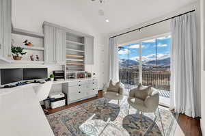 Office area featuring a mountain view, built in desk, built in shelves, vaulted ceiling, and dark hardwood / wood-style floors