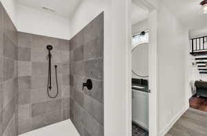 Bathroom featuring wood-type flooring, vanity, and a tile shower