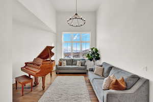 Sitting room featuring wood-type flooring, a high ceiling, and a notable chandelier