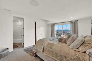 Bedroom featuring connected bathroom, light carpet, and a textured ceiling