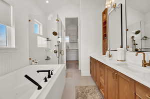 Bathroom with separate shower and tub, tile patterned flooring, vaulted ceiling, and vanity