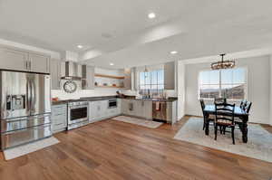 Kitchen featuring pendant lighting, appliances with stainless steel finishes, sink, a textured ceiling, and wall chimney range hood