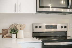 Kitchen with white cabinets, light stone countertops, and stainless steel appliances