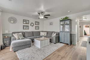 Living room featuring light wood-type flooring, ceiling fan, and a textured ceiling