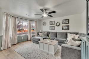 Living room featuring a textured ceiling, light hardwood / wood-style flooring, and ceiling fan