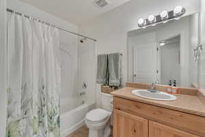 Primary Bedroom-Full bathroom with toilet, tile patterned floors, vanity, and shower / bathtub combination with curtain