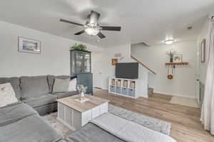 Living room featuring light wood-type flooring, ceiling fan, and a textured ceiling