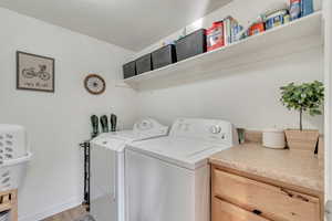 Main Floor Laundry room next to Kitchen with cabinets, light wood-type flooring, a textured ceiling, and washer and clothes dryer