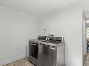 Washroom featuring separate washer and dryer and light hardwood / wood-style flooring