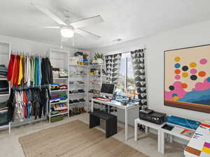 Carpeted home office featuring a textured ceiling and ceiling fan