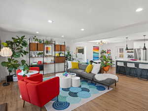 Living room with light wood-type flooring and an inviting chandelier