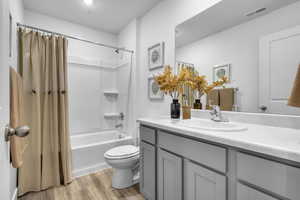 Full bathroom with vanity, toilet, hardwood / wood-style floors, and shower / bath combo with shower curtain