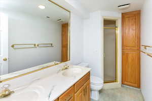 Bathroom featuring a shower with shower door, toilet, and vanity