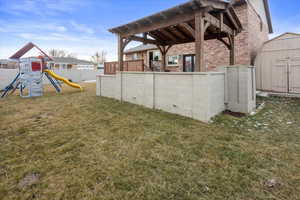 View of yard with a playground and a shed