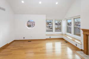 Unfurnished living room with light hardwood / wood-style floors and high vaulted ceiling