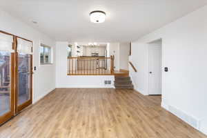 Unfurnished living room featuring light hardwood / wood-style flooring and an inviting chandelier