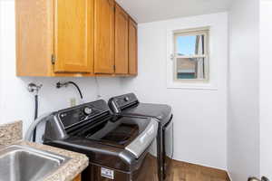 Washroom featuring cabinets, wood-type flooring, and washer and clothes dryer