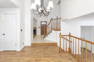 Foyer entrance featuring a towering ceiling, a chandelier, and light wood-type flooring