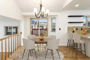 Dining room featuring a notable chandelier, light hardwood / wood-style flooring, and lofted ceiling