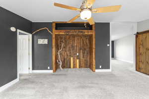 Interior space featuring carpet floors, ceiling fan, and a barn door