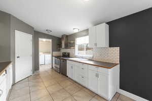 Kitchen with backsplash, white cabinetry, washer and dryer, and stainless steel appliances