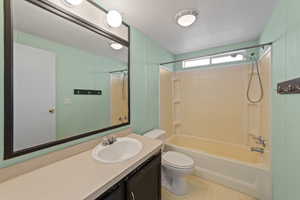 Full bathroom with a textured ceiling, toilet, vanity, and bathing tub / shower combination