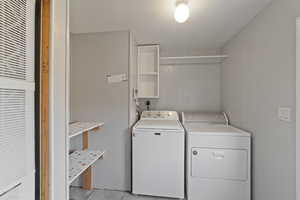 Washroom featuring light tile patterned floors, a textured ceiling, and washer and clothes dryer