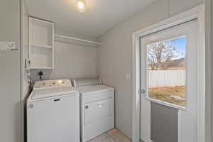 Clothes washing area with washing machine and clothes dryer, light tile patterned floors, and a textured ceiling