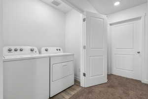 Laundry area featuring light carpet and independent washer and dryer