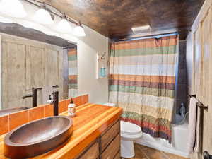 Full bathroom featuring tile patterned floors, toilet, vanity, and shower / bath combination with curtain