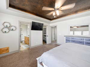 Bedroom with crown molding, ensuite bath, light carpet, a raised ceiling, and ceiling fan