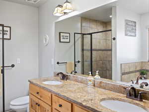 Bathroom with toilet, a shower with door, and vanity