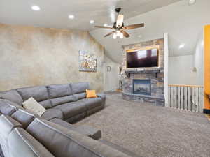 Living room with light carpet, vaulted ceiling, ceiling fan, and a fireplace