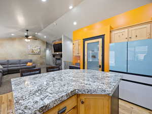 Kitchen featuring a fireplace, a center island, light hardwood / wood-style flooring, and white fridge