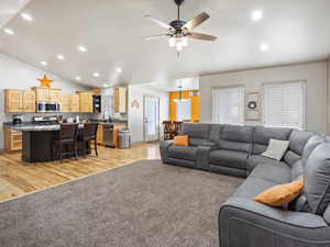 Living room featuring ceiling fan, sink, lofted ceiling, and light hardwood / wood-style floors