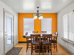 Dining area featuring light hardwood / wood-style floors, a textured ceiling, and a notable chandelier