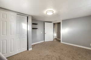 Unfurnished bedroom featuring a closet, a textured ceiling, and carpet floors