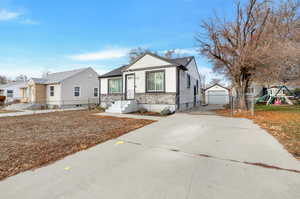 View of front facade featuring a playground, a garage, and an outdoor structure