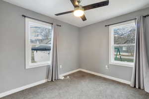 Carpeted spare room with plenty of natural light and ceiling fan