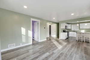 Unfurnished living room with sink and light hardwood / wood-style flooring