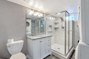 Bathroom featuring vanity, toilet, walk in shower, and a textured ceiling