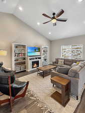 Living room featuring wood-type flooring, vaulted ceiling, and ceiling fan