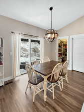 Dining room featuring lofted ceiling, dark hardwood / wood-style floors, and a chandelier