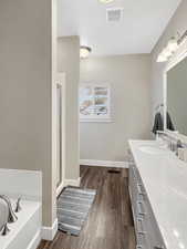 Bathroom with vanity, separate shower and tub, and wood-type flooring