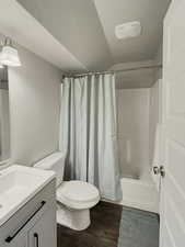 Full bathroom with wood-type flooring, toilet, shower / tub combo, and vanity