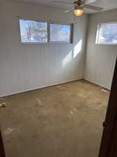 Empty room with ceiling fan and wood walls
