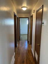 Corridor with dark hardwood / wood-style floors and a textured ceiling