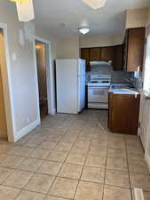 Kitchen featuring white appliances, dark brown cabinetry, a textured ceiling, sink, and light tile patterned floors