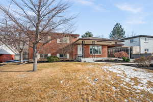 Tri-level home featuring covered porch and a front lawn